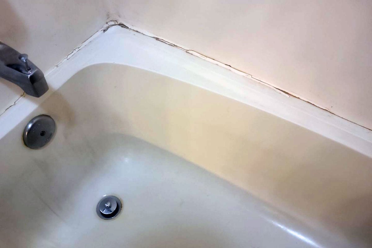 Mold growth on caulk around bathtub in apartment.