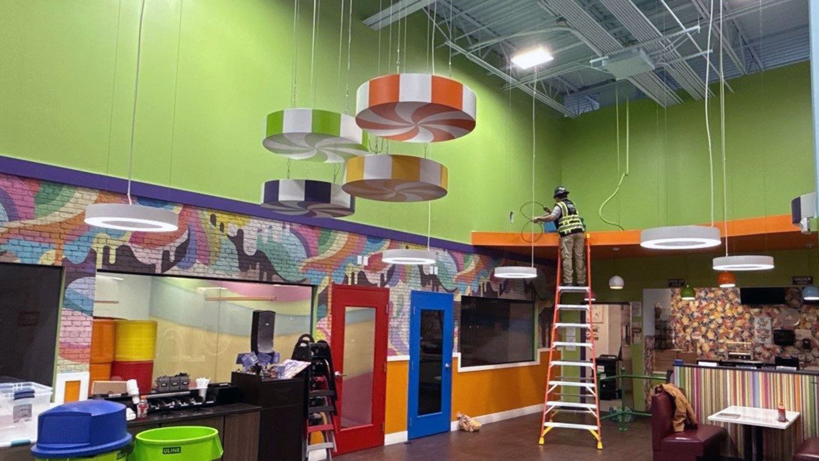 CRC restoration technician standing on ladder to clean soot from fire at indoor playground.