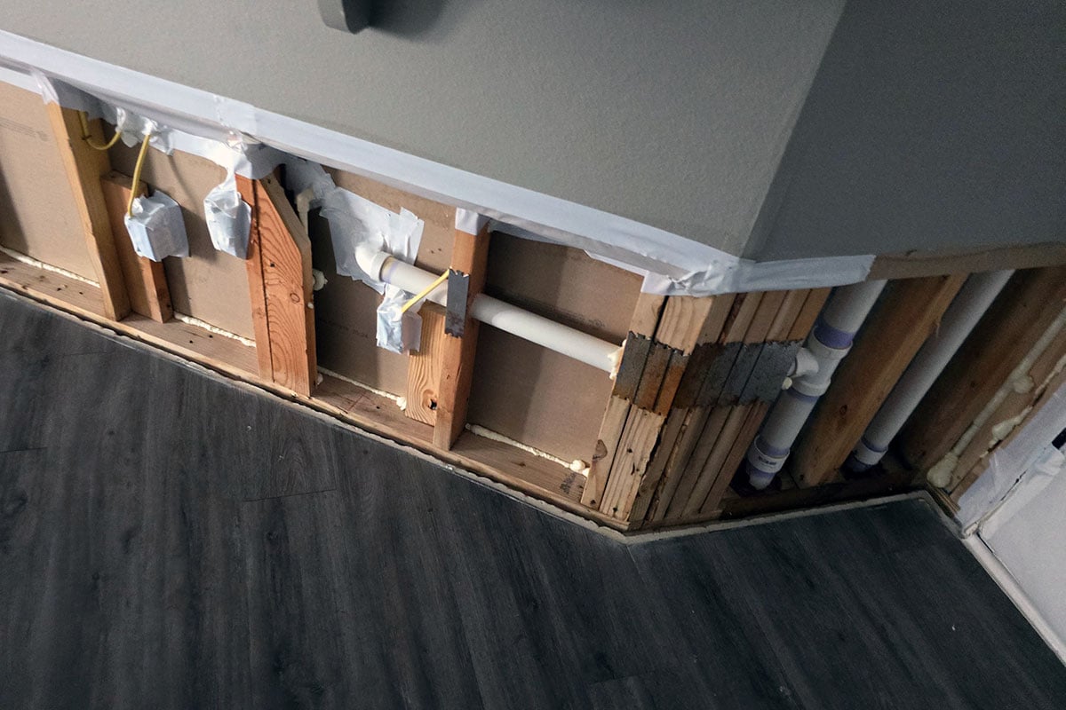 Flood cuts in island drywall exposing plumbing and electrical.