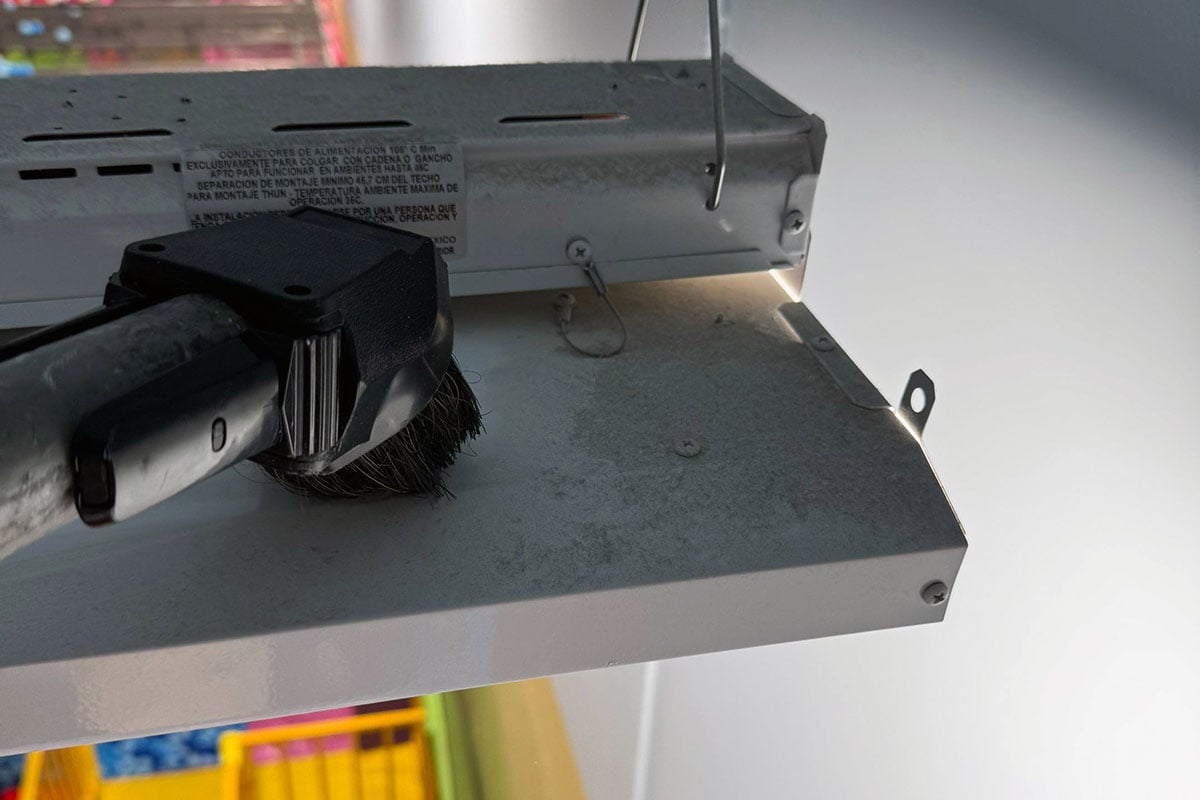 Vacuum removing soot from light fixture in indoor play facility.